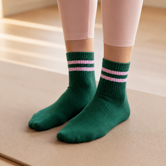 Female model wearing Verde Club green and pink Pilates grip socks on a mat – KORRHAUS