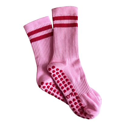Pink socks with red stripes and grip dots on a white background