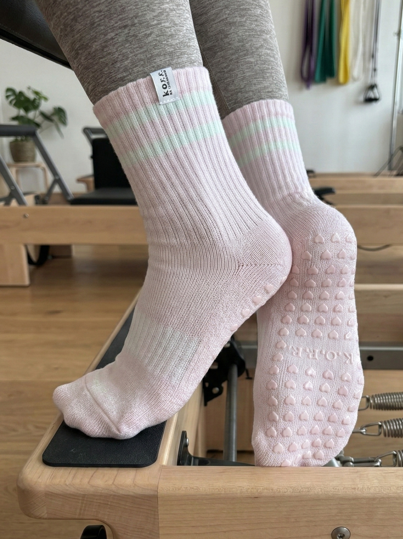 Person wearing pink socks with white soles on a Pilates reformer machine.
